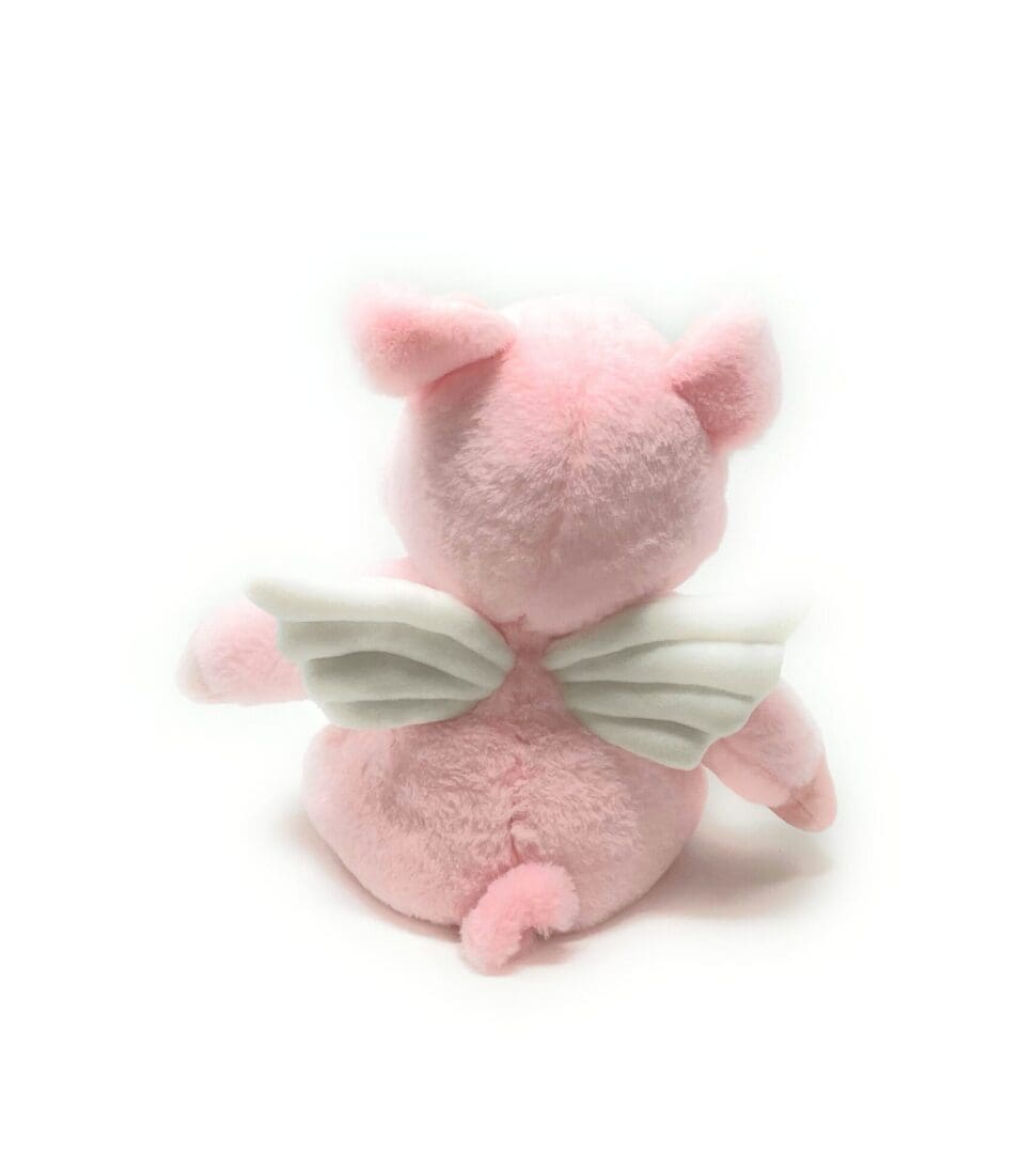 A pink stuffed animal with wings on its back.