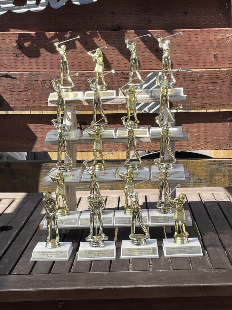 Gold golf trophy winners on wooden table.
