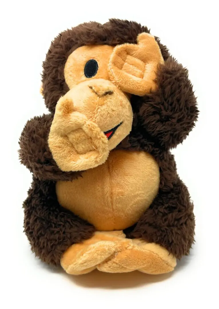 A stuffed monkey with its hands up to his ear.